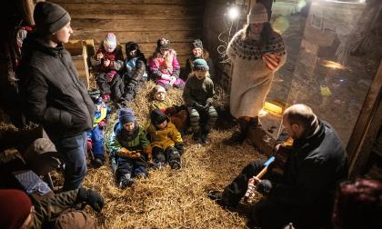 Prästen Stefan Äng till höger berättar och sjunger om stallkatten Kalles upplevelser i stallet. Barnen från församlingens tisdagsklubb lyssnar uppmärksamt.