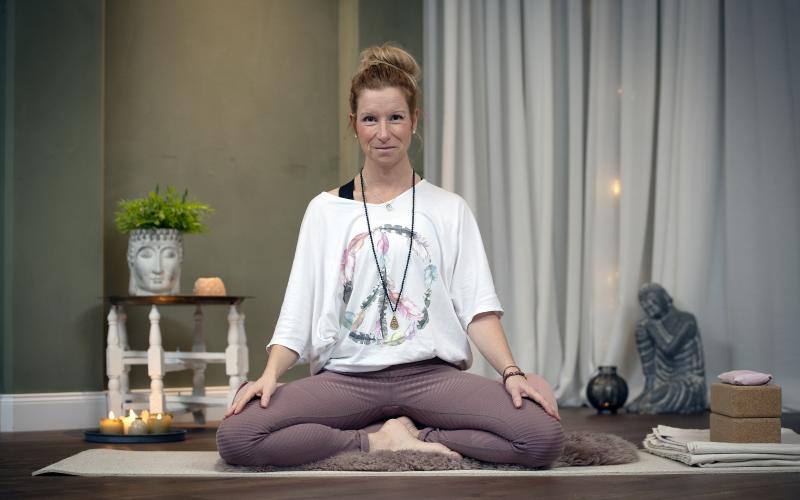 Kim Jansson sitter i skräddarställning i yogastudion