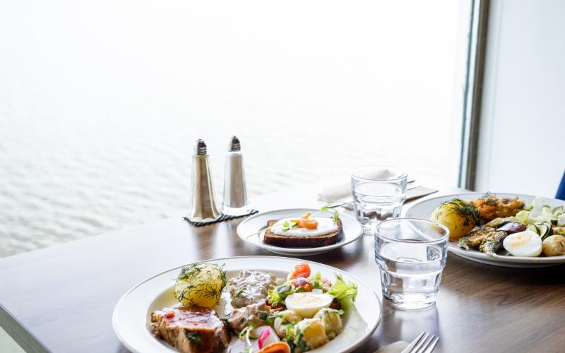 Tallrikar med mat som står på ett bord bredvid ett fönster med havsutsikt