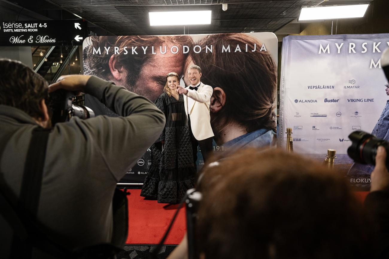 Här är fondväggen, med filmens finskspråkiga titel ”Myrskyluodon Maja”, som rört upp känslor på Åland. På röda mattan framför fonden står huvudrollsinnehavarna Amanda Jansson och Linus Troedsson.