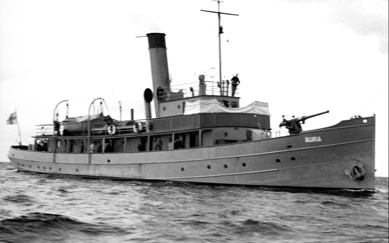 Sjöbevakningens Aura användes under krigsåren som eskortfartyg, utrustat med två 75 mm sjömålskanoner, två 20 mm luftvärnskanoner, samt sjunkbombskastare. Här i samband med eskortverksamhet utanför Kobbaklintar den oroliga sensommaren 1942. SA-kuva. 