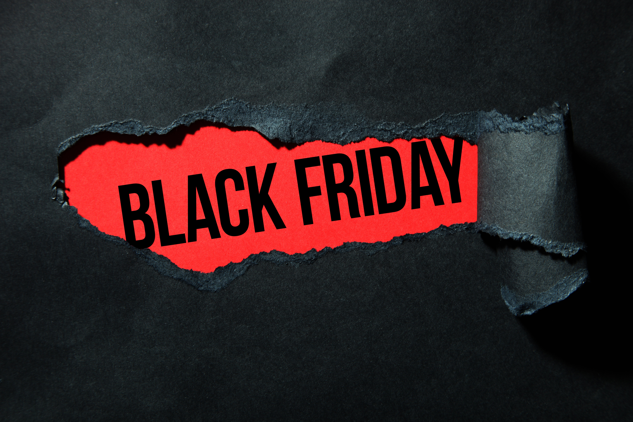 Black torn paper and the inscription "black friday" on a red background.