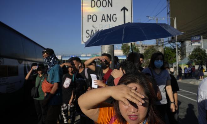 Pendlare försöker undvika solen under värmeböljan i filippinska Quezon City tidigare i april.
