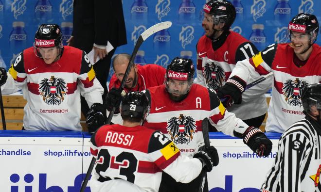 Österrikes tvåmålsskytt Peter Schneider, i mitten, jublar och gratuleras av NHL-forwarden Marco Rossi, Minnesota.