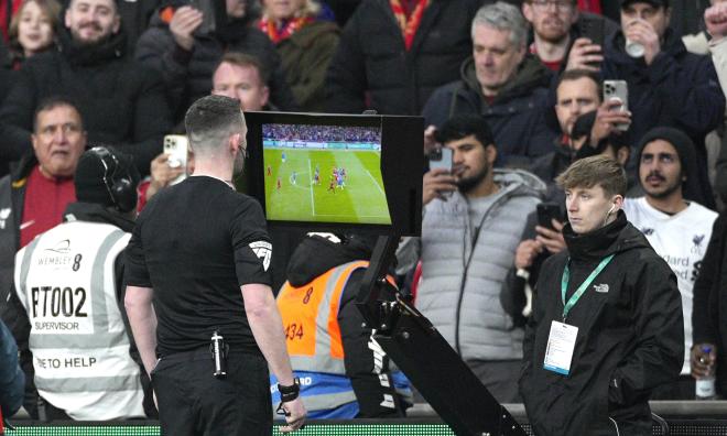 En engelsk fotbollsdomare kollar på VAR-skärmen för att sedan ta beslut.