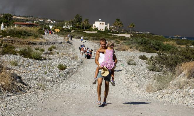 Turister flyr undan bränderna som härjade på Rhodos förra året. Arkivbild.
