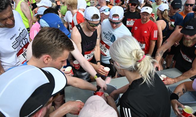 Törstiga löpare försöker få vatten vid vätskekontrollen på Torsgatan under Stockholm Marathon på lördagen.