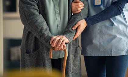 Close up hands of caregiver doctor helping old woman at private clinic. Close up of hands of nurse holding a senior patient with walking stick. Elder woman using walking cane at nursing home with nurse holding hand for support. 