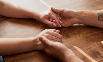 Cropped shot of a man and woman holding hands in comfort on a table