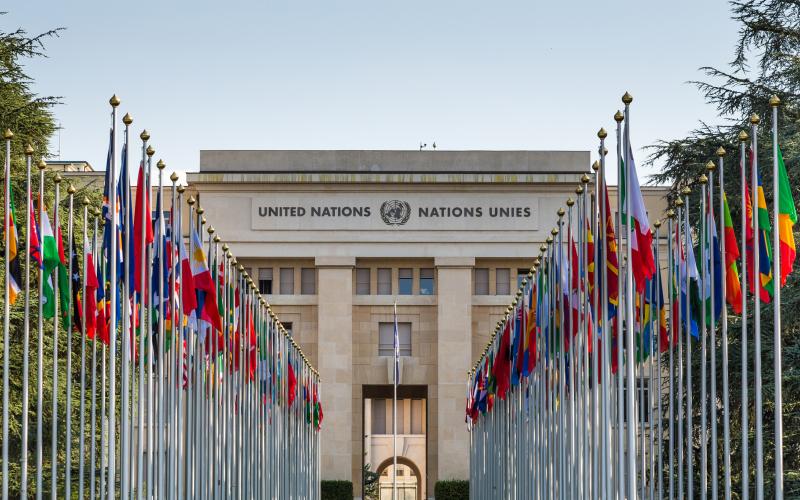 Geneva, Switzerland - 6 August, 2019: color image depicting the exterior architecture of the United Nations (UN) building in the city of Geneva, Switzerland. The front of the building is lined with many flags and flagpoles, representing all the member nations of the UN. Room for copy space.