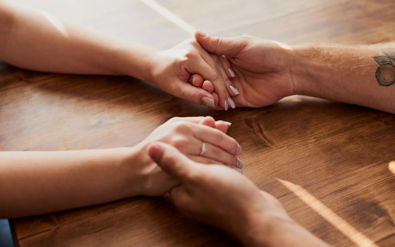 Cropped shot of a man and woman holding hands in comfort on a table