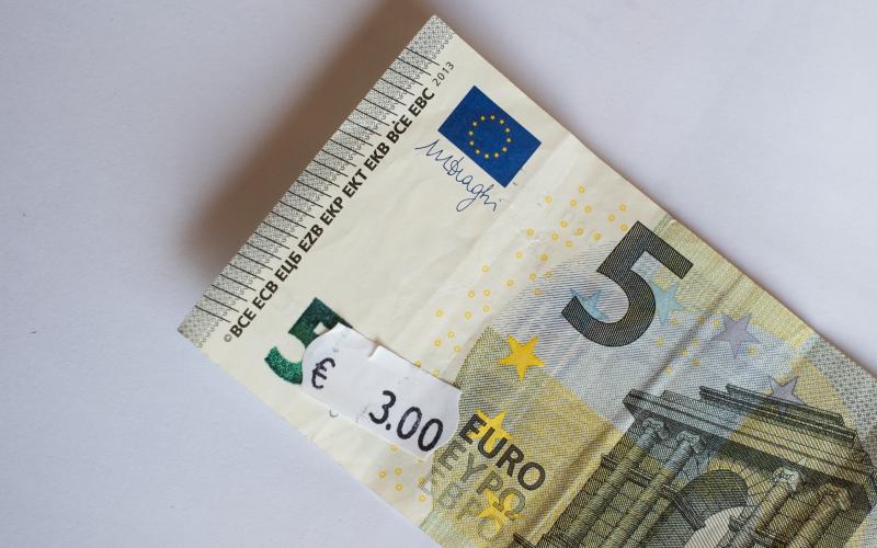 Five euro banknote with three euro price tag. Selective focus on label.