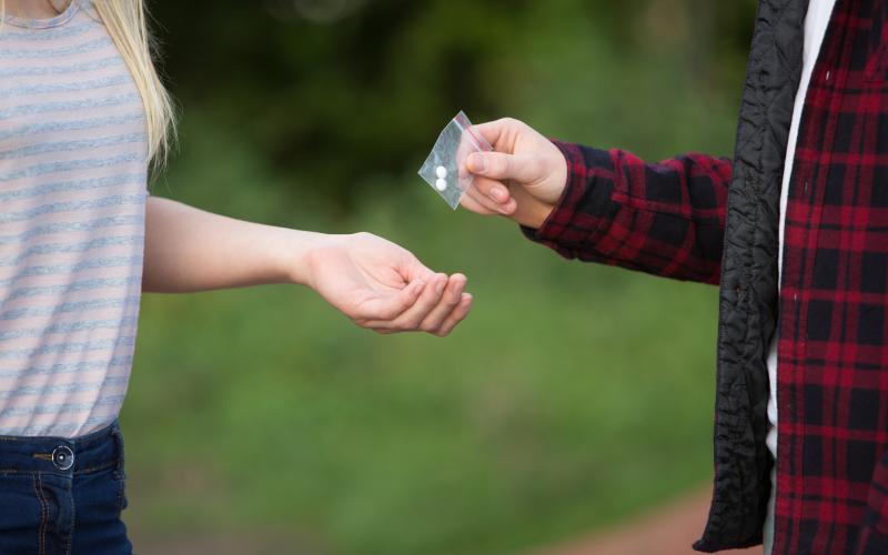 Teenage Girl Buying Drugs In Playground From Dealer