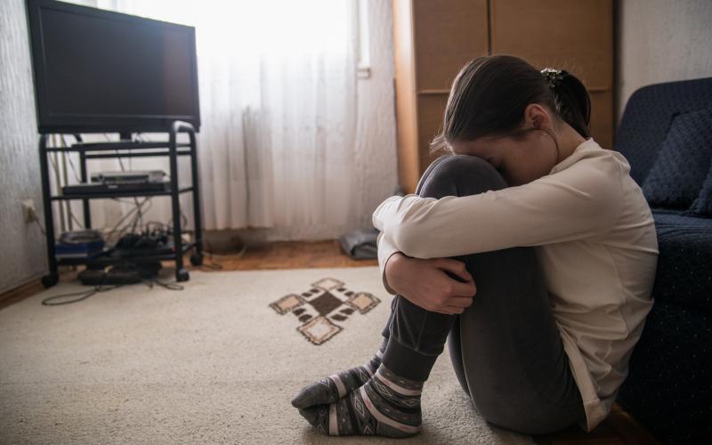 Teen woman with headache holding her head in her living room during the day 