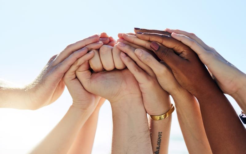 Cropped shot of a group of people joining hands in solidarity