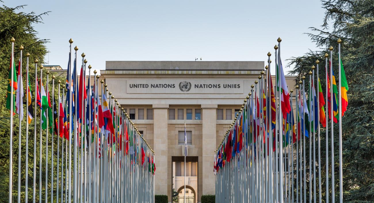 Geneva, Switzerland - 6 August, 2019: color image depicting the exterior architecture of the United Nations (UN) building in the city of Geneva, Switzerland. The front of the building is lined with many flags and flagpoles, representing all the member nations of the UN. Room for copy space.